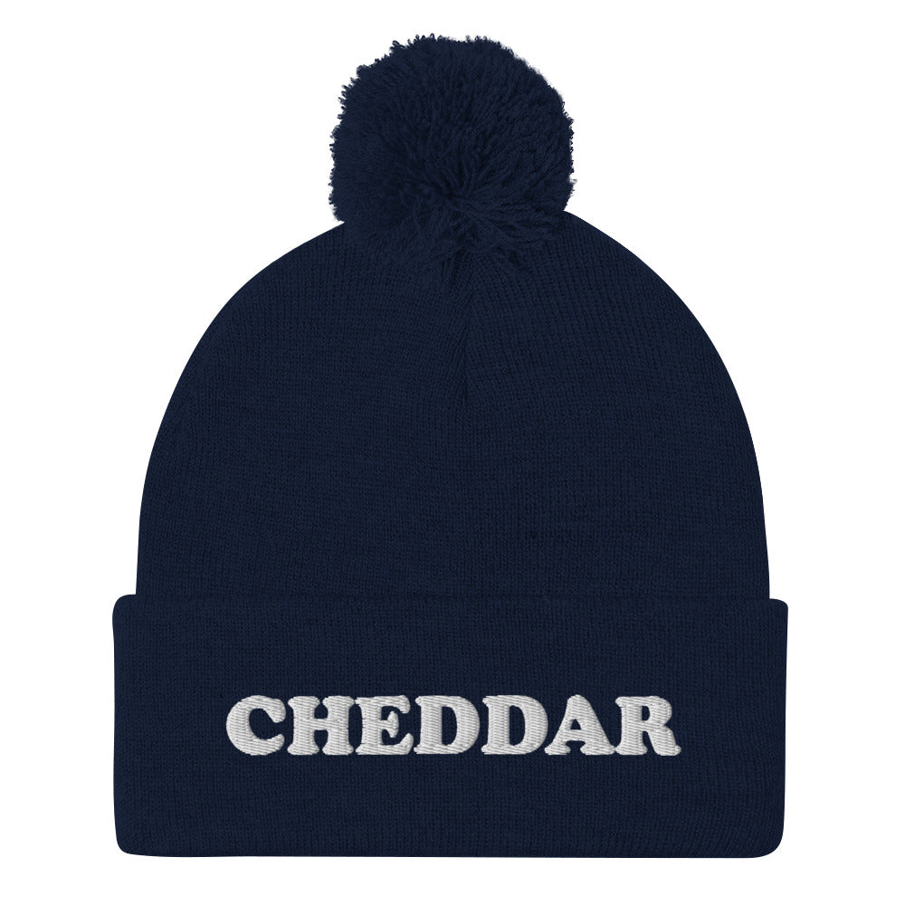 Navy Do you love cheddar cheese? Looking for a funny foodie gift? This warm and cozy, embroidered beanie is just what you need. It's a classic pom pom beanie with "Cheddar", expertly embroidered on the front. The perfect funny beanie for cheese lovers, cheddar enthusiasts and foodies of all kinds.