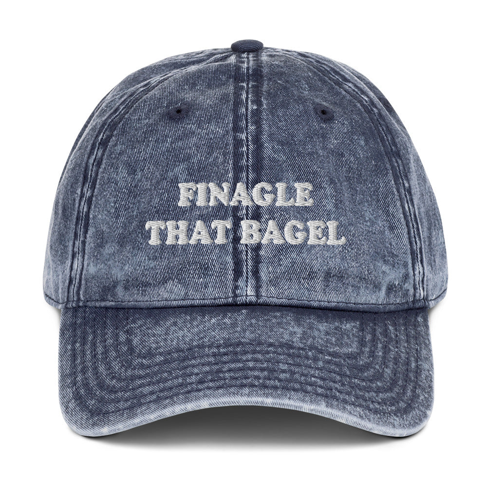 Navy Finagle That Bagel Hat - Love Bagels? Looking for a funny gift for a bagel enthusiast? This Unique Bagel Hat is just what you need. It's comfortable, has an adjustable closure, and comes in a variety of colors with "Finagle That Bagel", on the front. Eat your favorite bagels in this funny food dad hat. Perfect for bagel lovers and beyond.